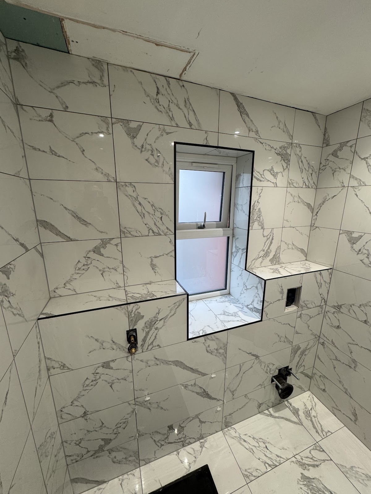White marble-effect bathroom wall tiling with feature window reveal